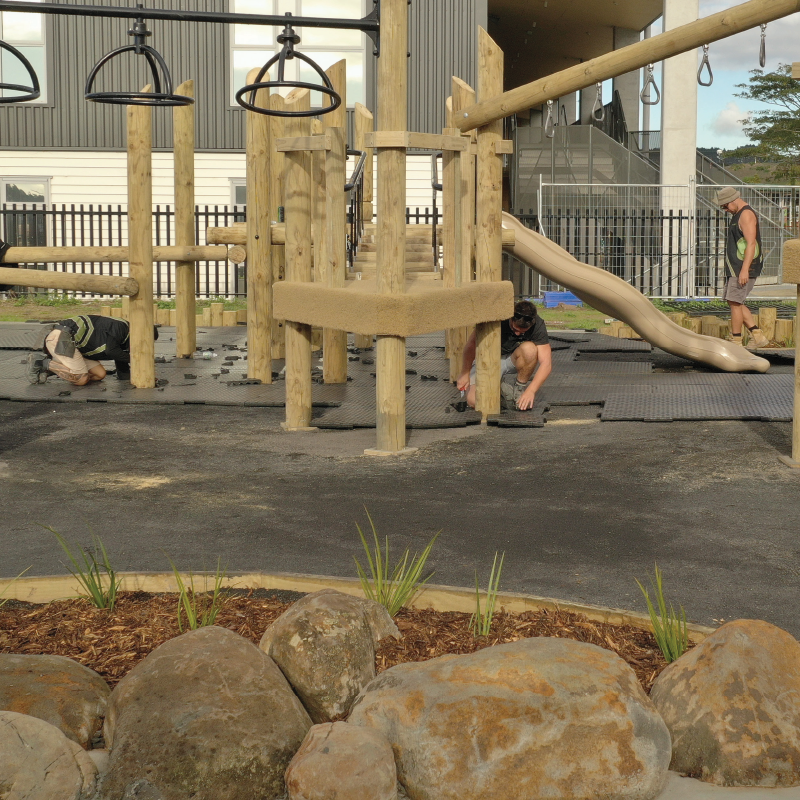 A wide shot of playground builders installing softfall shockpad