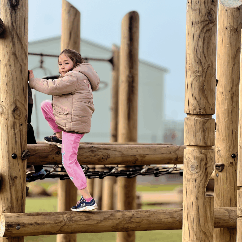 Girl climbing timber playground fort