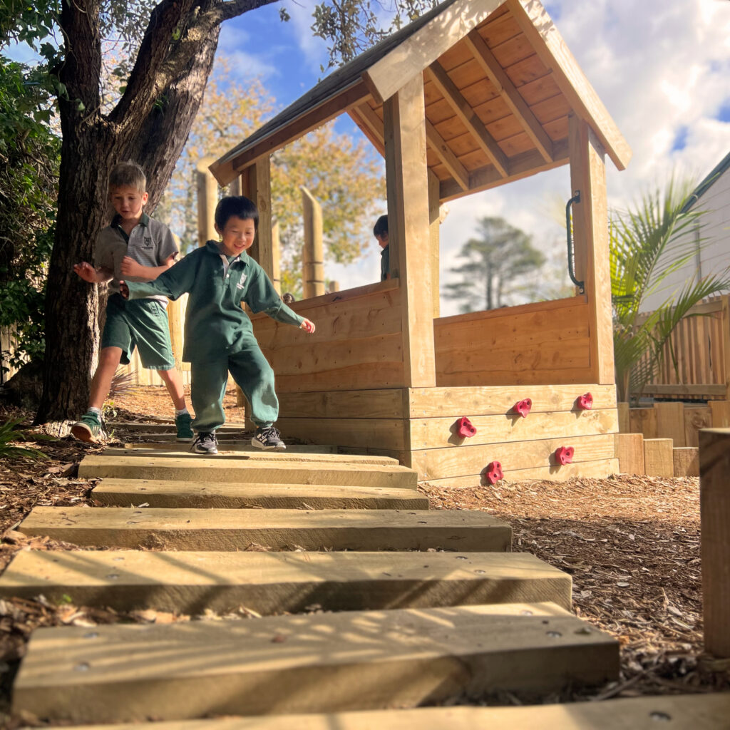 Children playing next to a nature cubby house
